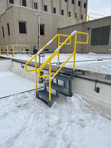 A compact set of industrial safety stairs, featuring bright yellow handrails for enhanced visibility and safety compliance. The sturdy fabricated structural steel construction ensures durability and stability. The steps are designed with anti-slip grating, providing secure footing in demanding environments. The yellow handrails, crafted through precise metal pipe welding and welding repair services, highlight the dedication of structural iron and steel workers to creating safe access solutions. This setup exemplifies superior fence and railing standards, making it an essential component for maintaining industrial safety protocols.