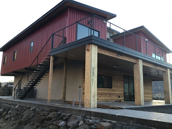 A modern home with a striking red exterior, featuring a durable balcony and stair railing system crafted from fabricated structural steel. This setup highlights the robust construction typical of beam steel structure designs, ensuring both safety and aesthetic appeal. The balcony, accessed via a sleek staircase, is bordered by deck railings metal that offer a contemporary touch. This project underscores the proficiency of structural steelwork fabricators and the expertise involved in aluminum welding and welding cast aluminum processes. The deck with railings design integrates seamlessly with the home's architecture, showcasing the importance of superior fence and railing installations in modern residential construction.